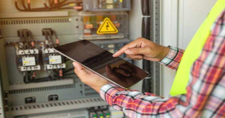 Close up hand of engineer or electrician man working check the electrical system with tablet at factory.